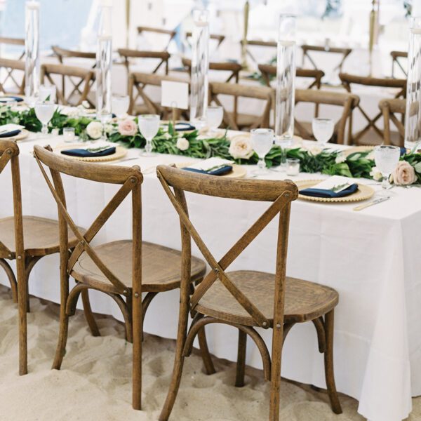 tables set up for family style seating at long tables with cross back chairs for wedding reception