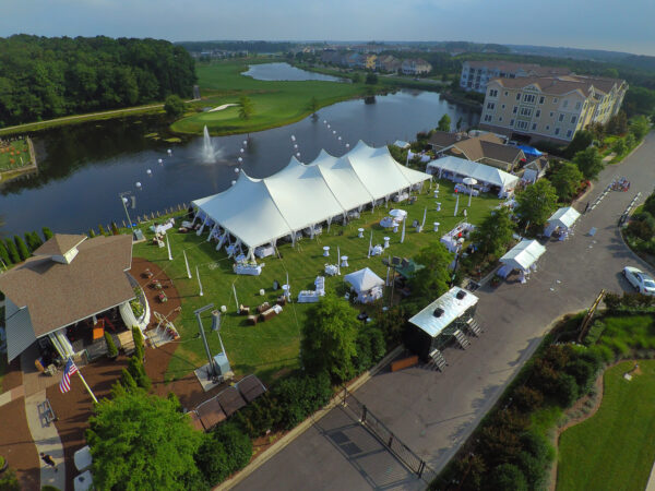 60x120 high peak pole tent set up on grass overlooking lake