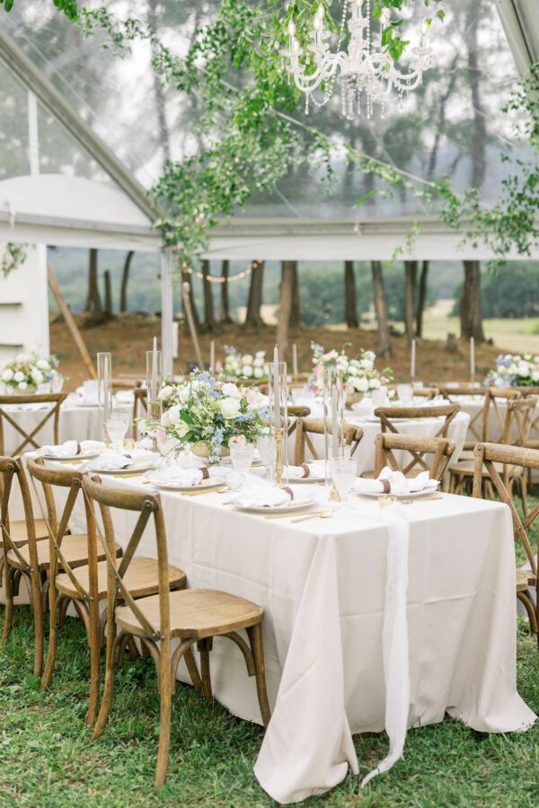 clear top tent with tables with white linen and cross back chairs