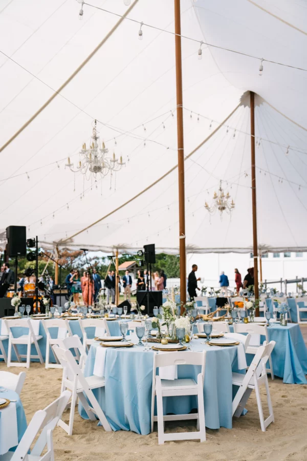 wedding tent with white tuscan bistro lighting and chandeliers on sand