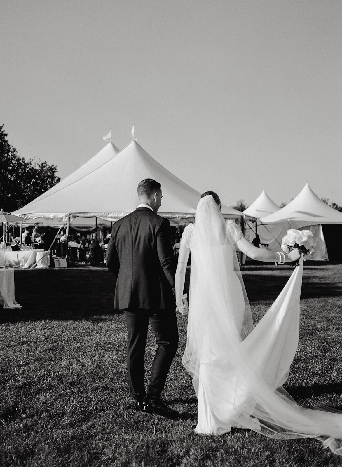 bride and groom walking toward wedding tent