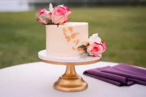 wedding cake with pink flowers on gold stand