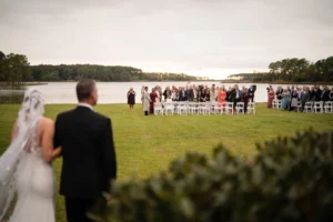 bride walking towards her waterfront wedding ceremony with guests sitting in chairs