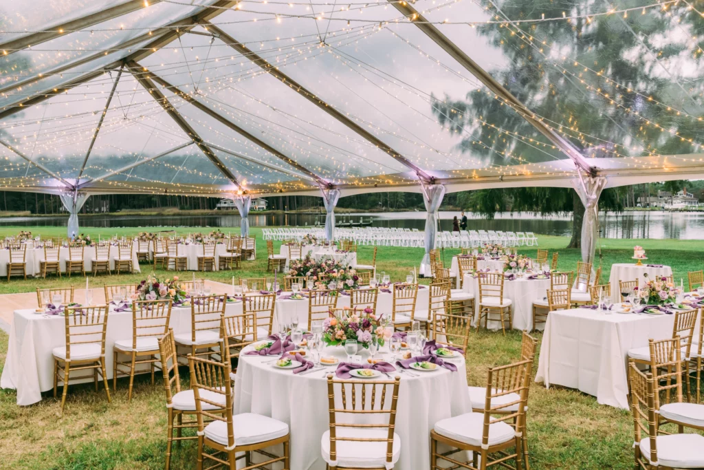 clear tent set up on grass with tables and chairs for wedding