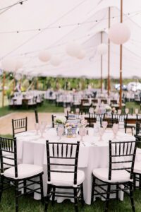 wedding tent with paper lanterns, round tables with white linens, black chairs