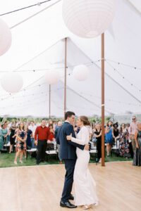 bride and groom dancing under large white tent
