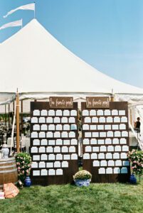 seating chart on board set up in front of white wedding tent