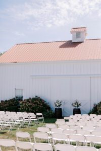 white ceremony chairs set up in front of barn