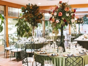 Indoor tablesetting with large trumpet vase arrangements of greenery, pink and purple roses