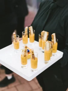 Catering staff holding a tray of shot glasses with a soup