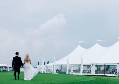 bride and groom walking towards sailcloth wedding tent on lawn