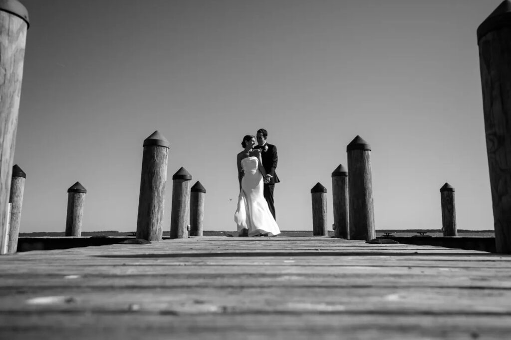 bride and groom standing on dock black and white photo