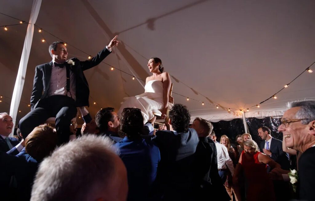 bride and groom held up on chairs celebrating at their wedding reception