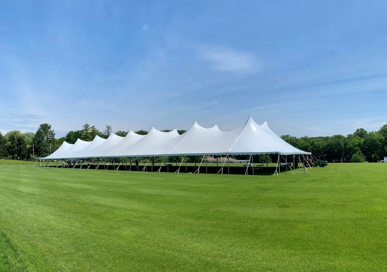 Landscape image of a large pole tent on a campus green