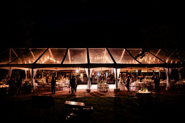 clear top tent at night with bistro lighting glowing though translucent tent top
