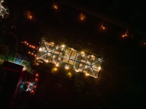 Drone aerial view of a 40x120 cleartop tent light up at tent