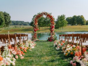 Floral ceremony arch and floral aisles with light fruitwood folding chairs