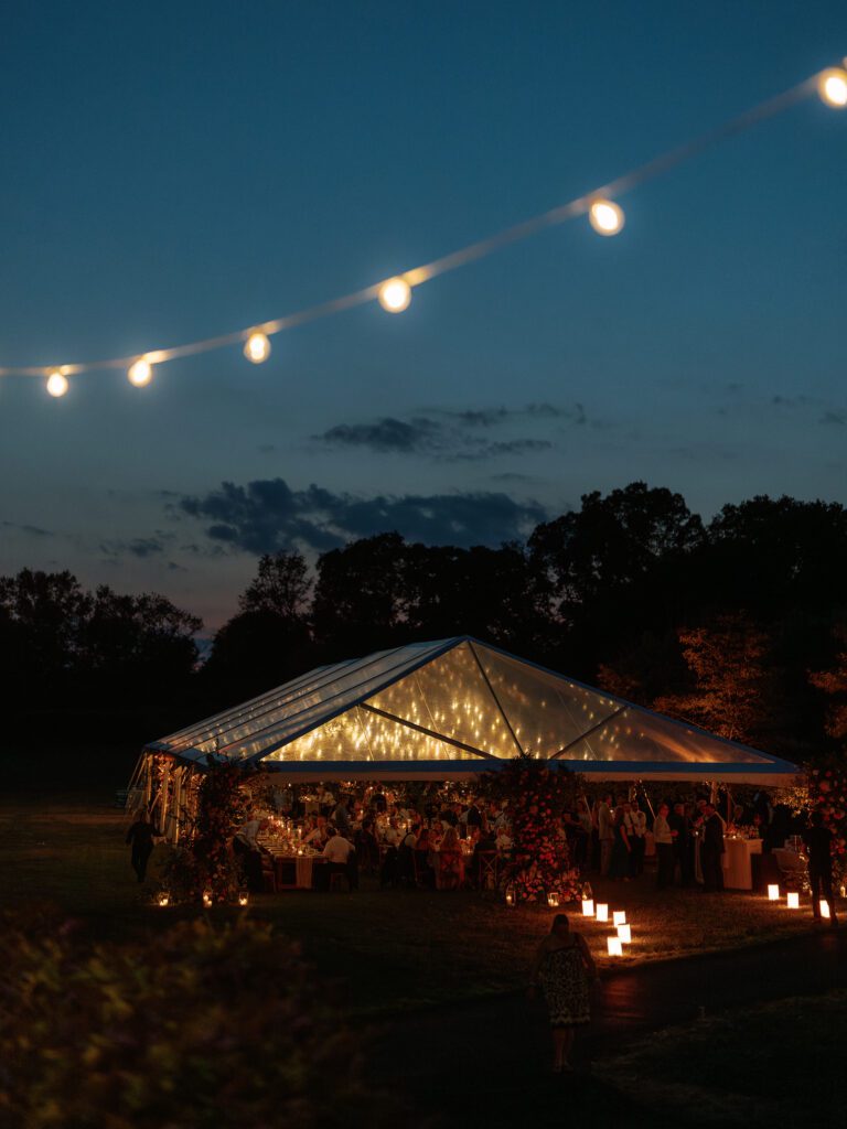 clear ceiling tent in evening with bistro lighting glowing through translucent top