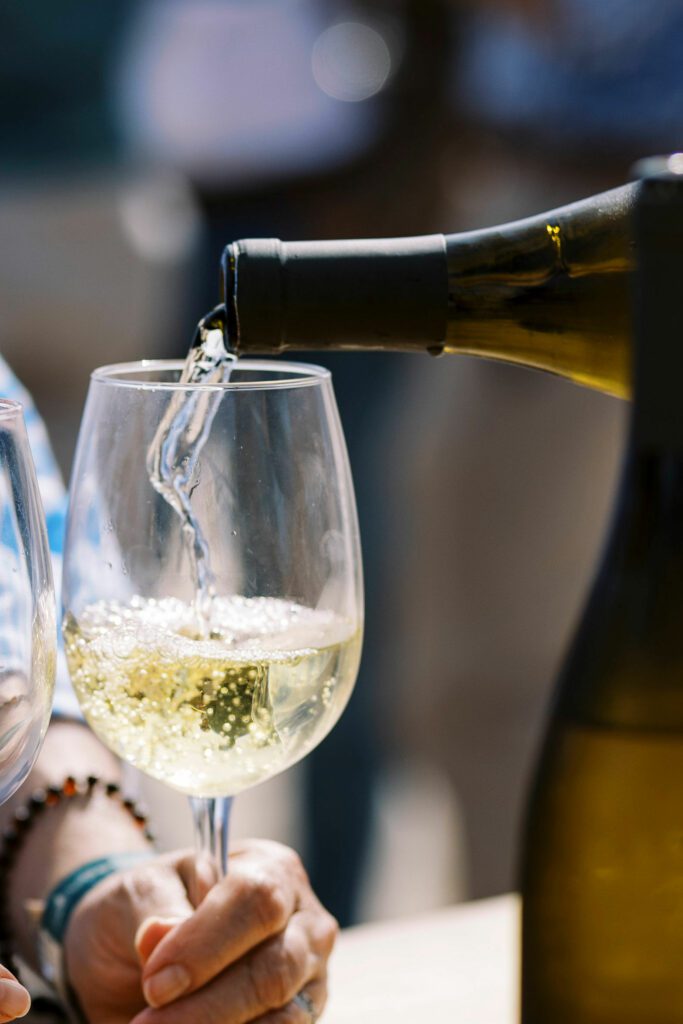 white wine pouring into stemmed wine glass