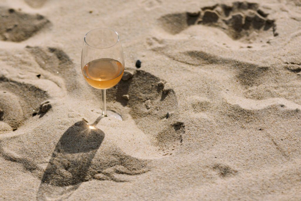 glass of rose wine on sandy beach