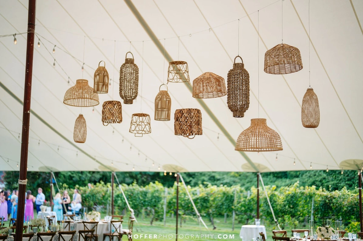 wedding tent with rattan lanterns suspended from ceiling.