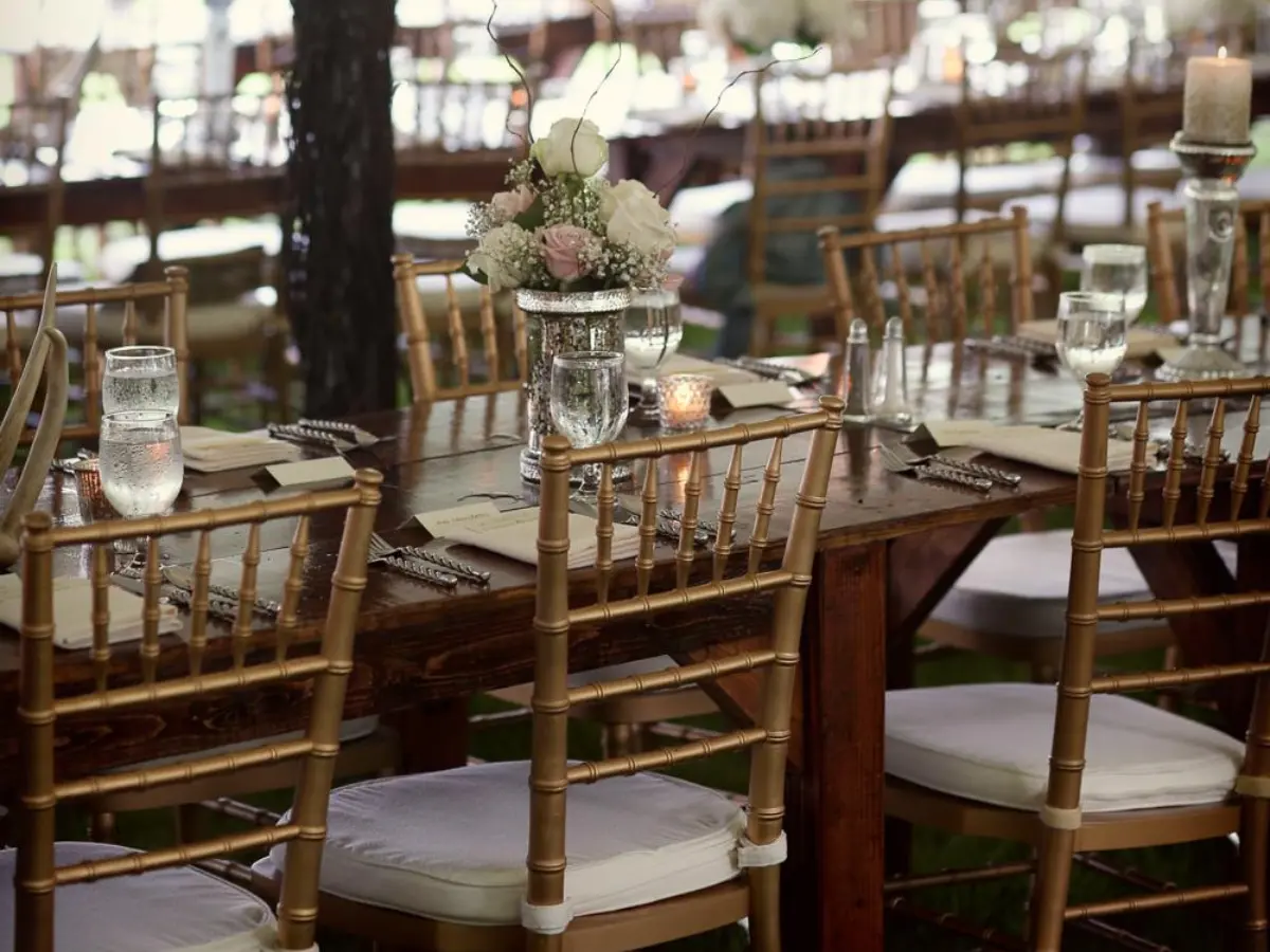 Gold Chiavari chairs set at a farmhouse table for a reception