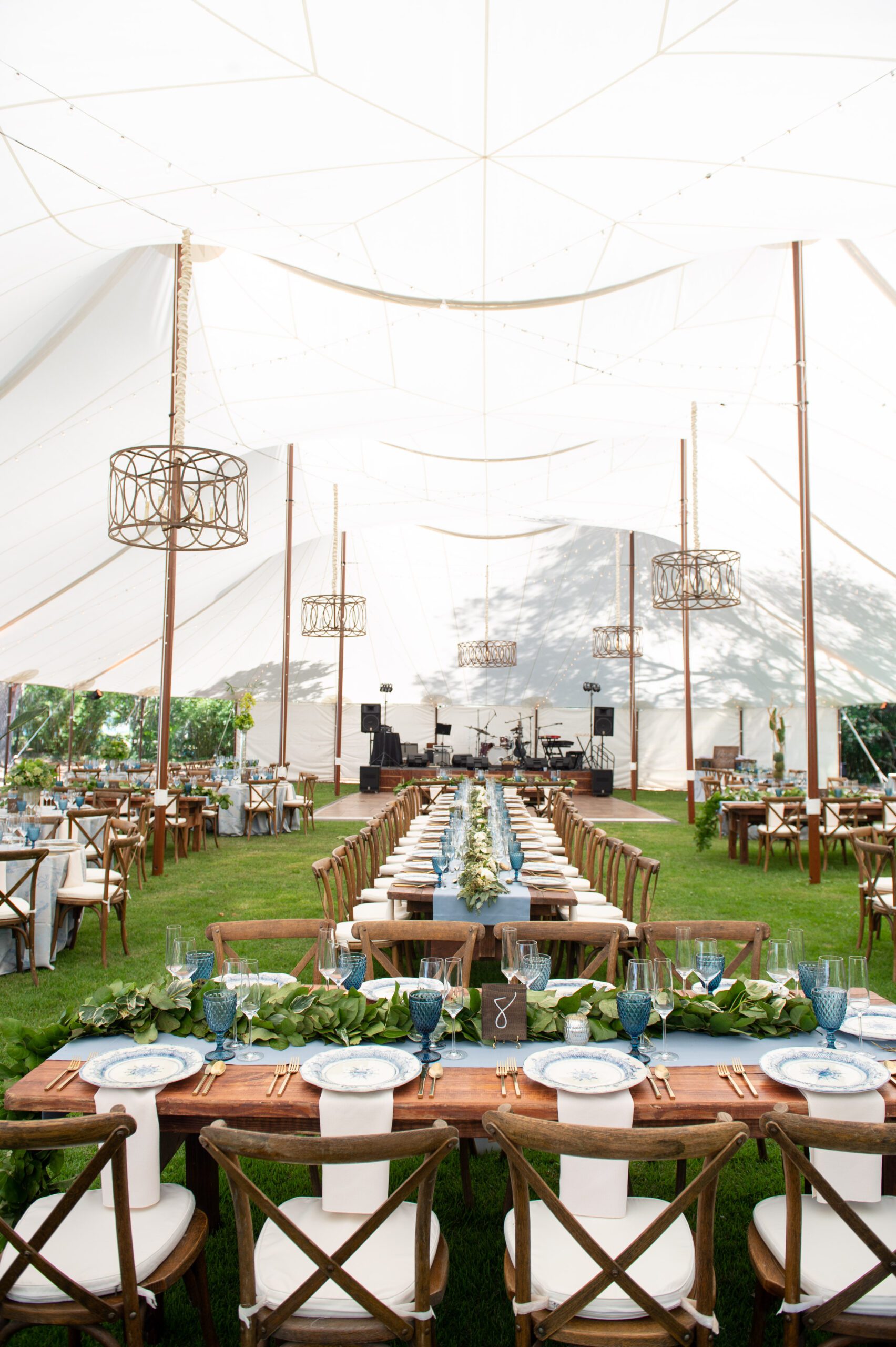 sailcloth wedding tent set up with farmhouse tables and crossback chairs