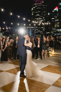 bride and groom dancing with overhead lighting on white and wood checkered dance floor