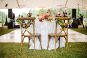 cross-back chairs set up at sweet heart table under wedding tent