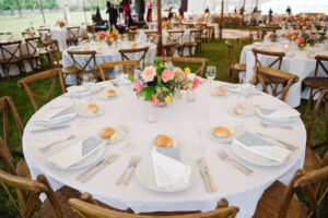 round tables with wooden chairs set up for tented wedding reception