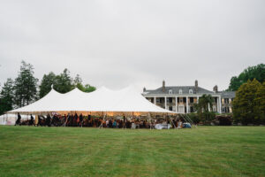 large wedding tent set up on lawn in front of stone estate house in Malvern PA