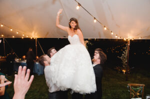 bride getting lifted up in chair during wedding reception dance