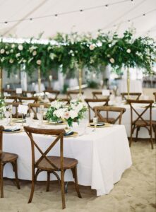 wedding tent set up on sand with crossback chairs and long guest tables