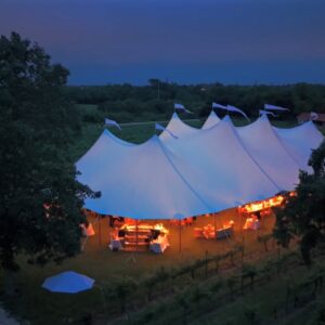 sailcloth style wedding tent photo from drone with tent lighting glowing at dusk
