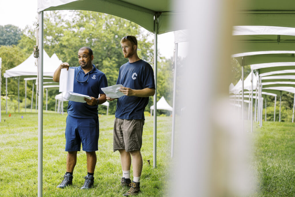 collective event group operations team looking at paperwork while installing tents
