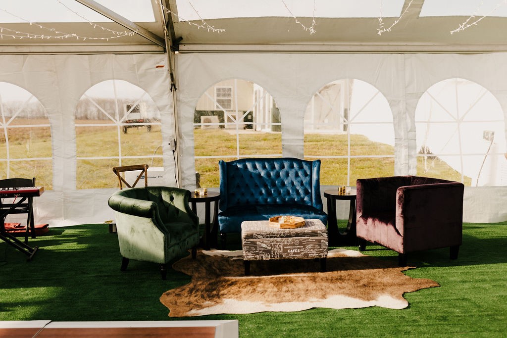 lounge seating area with blue sofa and chairs set up under a tent