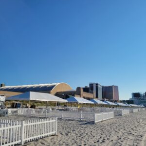 white picket fence set up on beach in front of event tents for festival